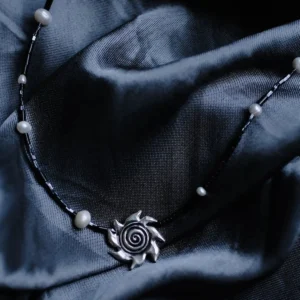 Black bead and pearl necklace with an oxidized spiral sun pendant on satin