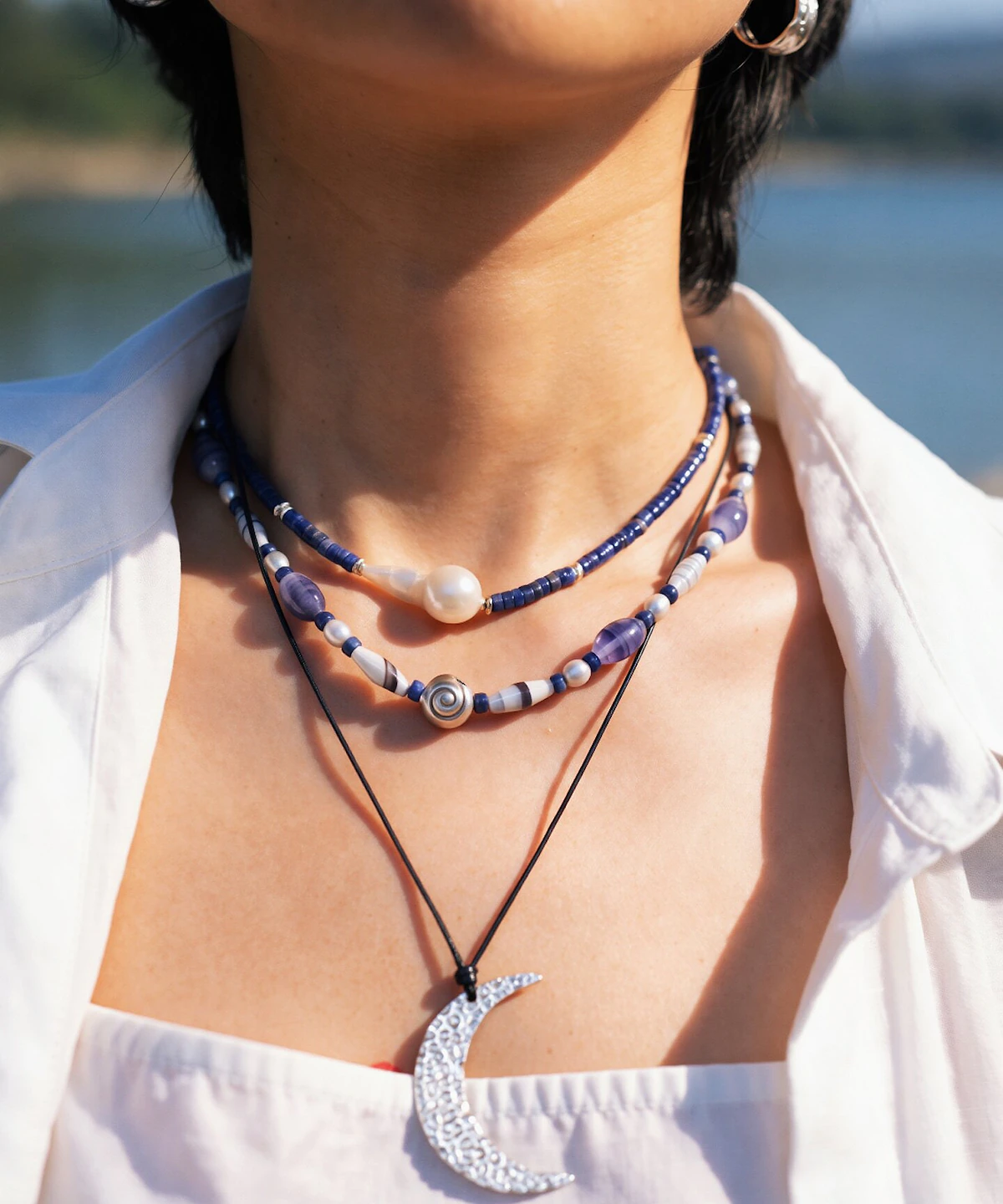 Blue agate necklace layered with a pearl strand and long silver pendant