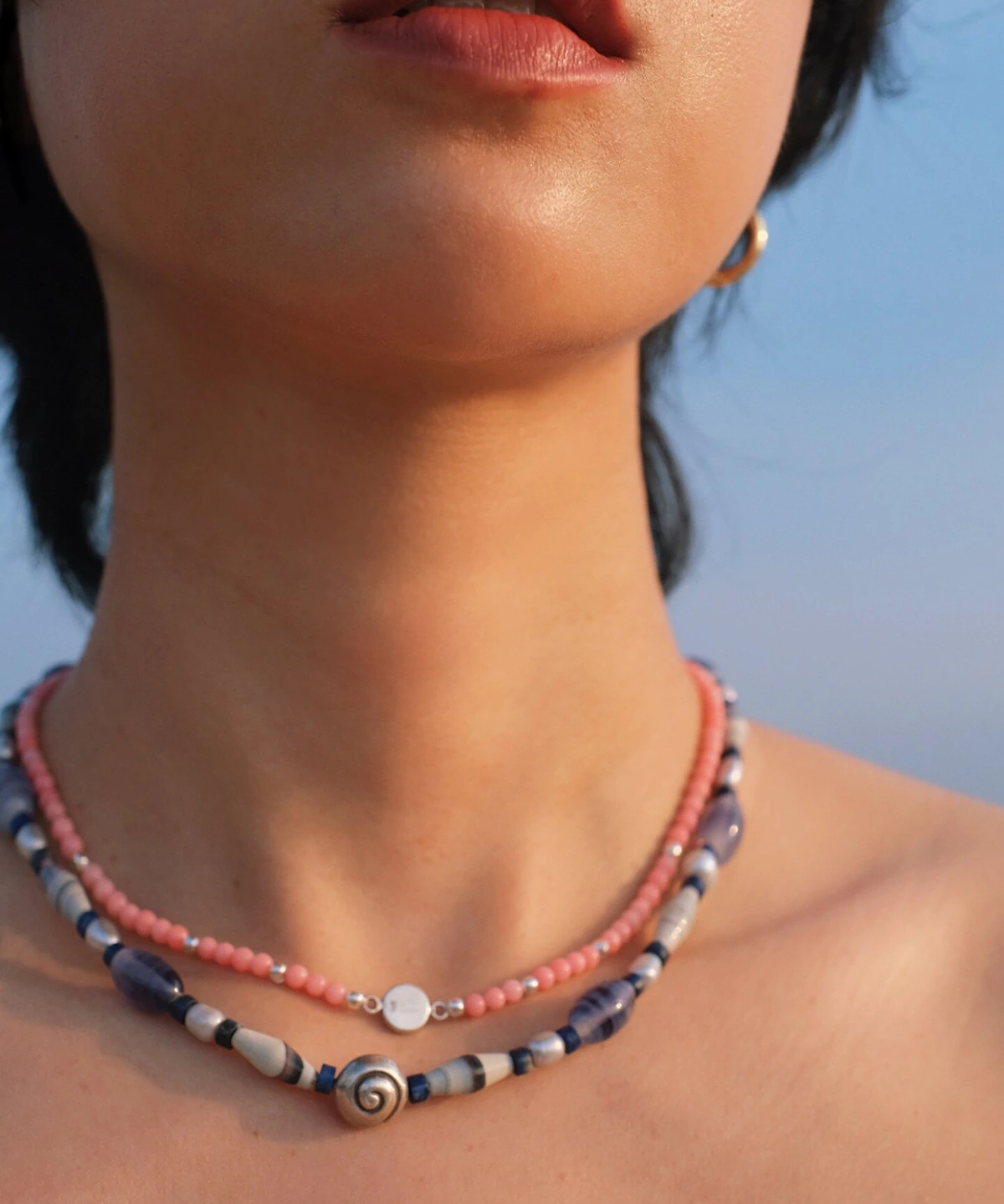 Blue agate necklace layered below a pink rhodonite necklace at the collarbone