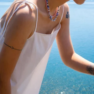 Blue agate necklace worn at the collarbone in a seaside profile portrait