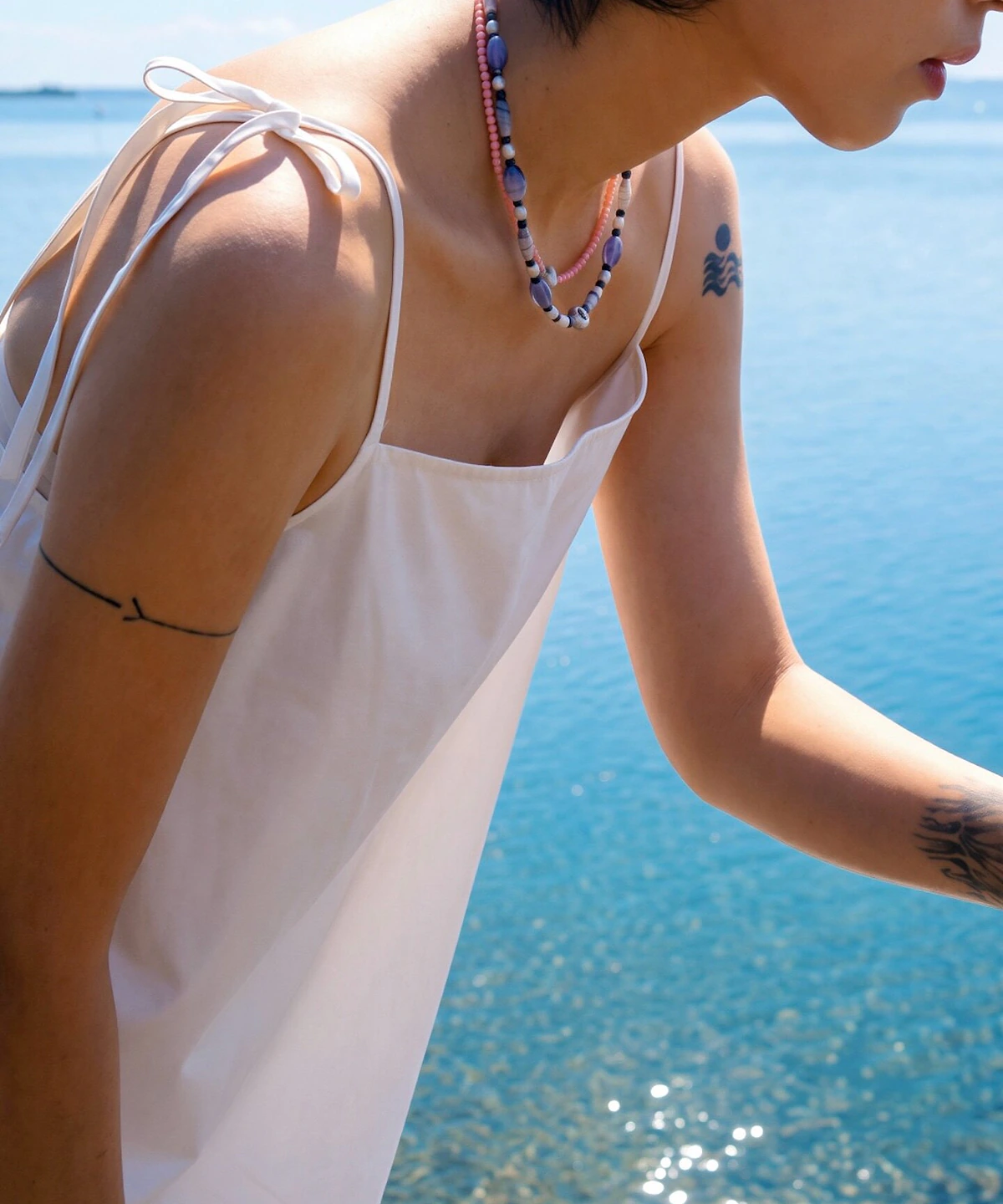 Blue agate necklace worn at the collarbone in a seaside profile portrait