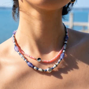 Blue agate and silver spiral shell necklace layered with pink beads in sunlight