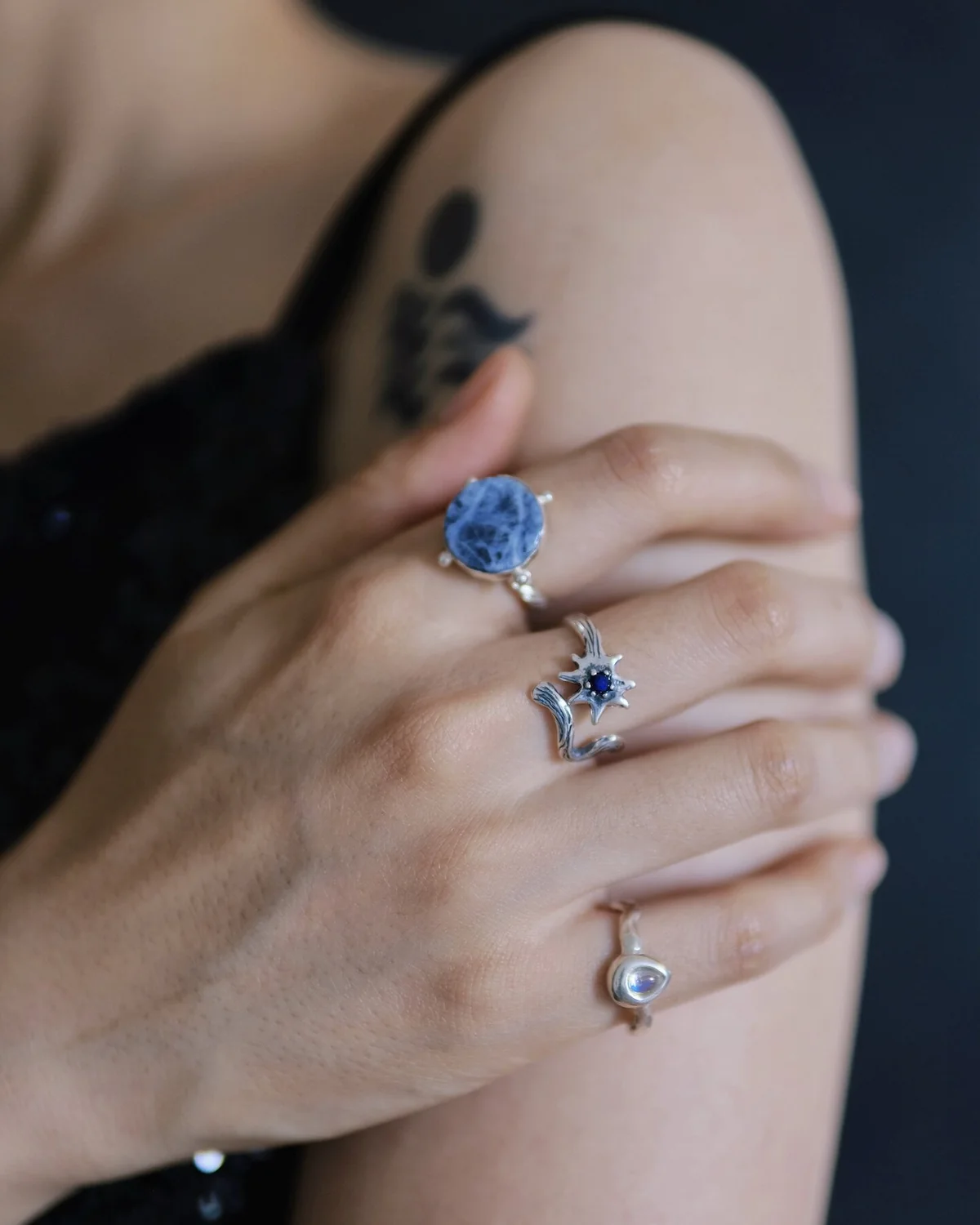 Blue stone and celestial silver rings arranged across one hand