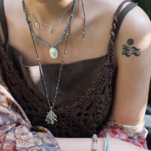 Dragonfly necklace layered with shorter silver charms and a long botanical pendant