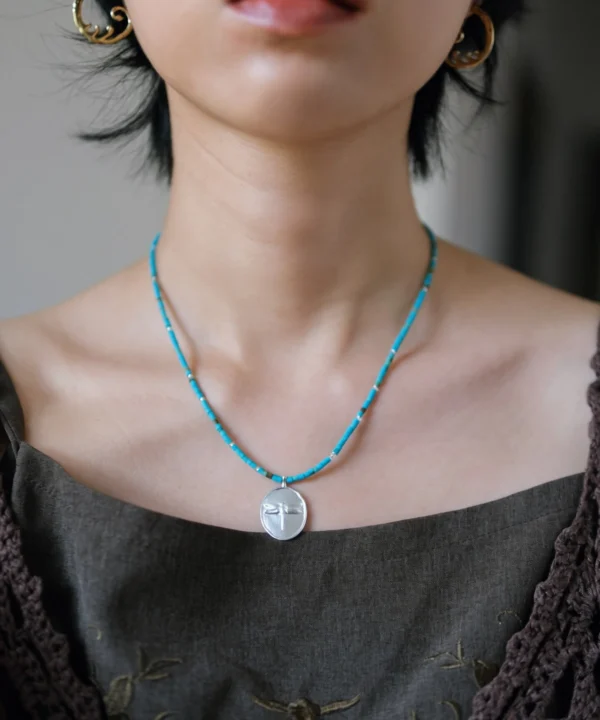Dragonfly necklace in S925 silver with blue-green glass beads, worn at the collarbone