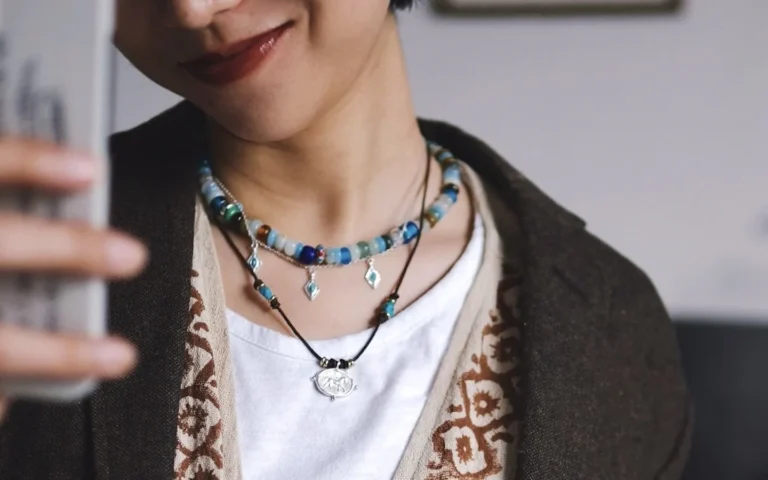 Three necklaces layered over a white T-shirt and brown cardigan, with amazonite beads, turquoise charms and a horse pendant