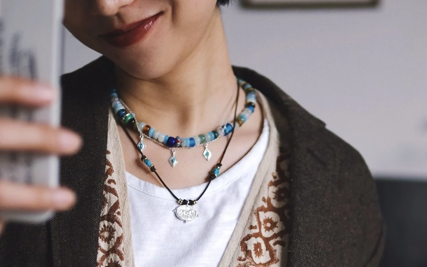 Three necklaces layered over a white T-shirt and brown cardigan, with amazonite beads, turquoise charms and a horse pendant