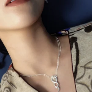 Infinity-shaped silver snake necklace worn from a reclining side angle