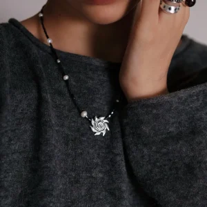 Light in the Dark necklace worn with a charcoal knit and layered rings
