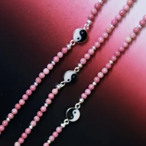 Three rhodonite yin yang necklaces showing natural pink bead variation