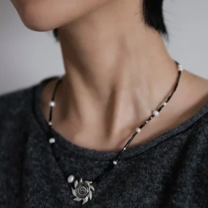 Oxidized silver sun necklace worn over a charcoal grey knit top