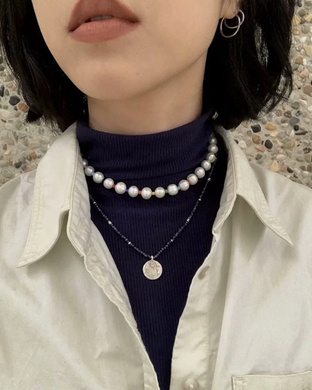 Layered Necklaces Over a Turtleneck Pearl strand and dark beaded coin pendant necklace layered over a navy turtleneck