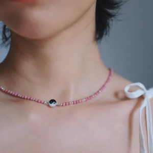 Pink rhodonite necklace with a black-and-white yin-yang centre worn at the collarbone