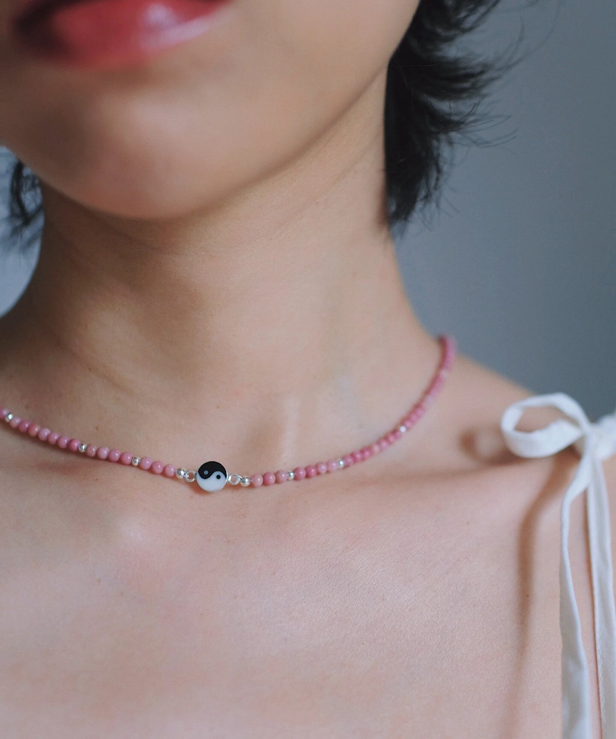 Pink rhodonite necklace with a black-and-white yin-yang centre worn at the collarbone