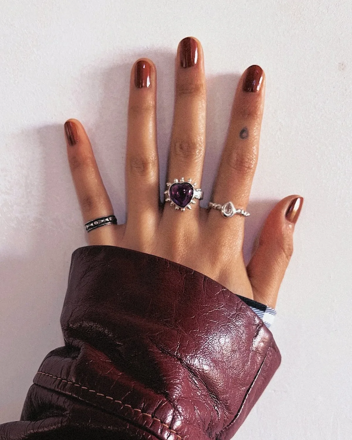 Purple heart-shaped gemstone ring balanced by two smaller rings across the hand