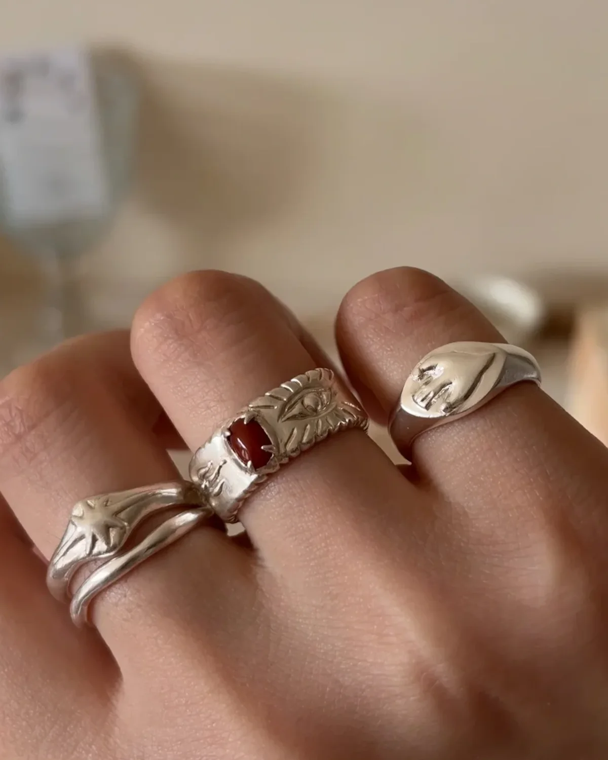 Red agate ring in textured silver worn with lower silver bands