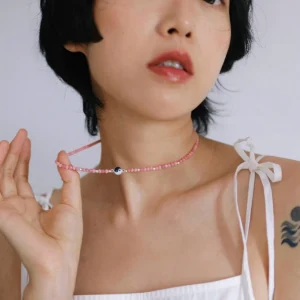 Rhodonite yin yang necklace held at the collarbone to show its scale