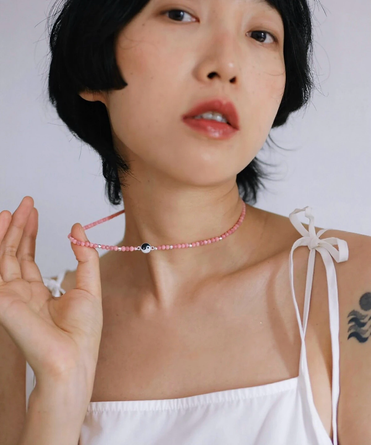 Rhodonite yin yang necklace held at the collarbone to show its scale