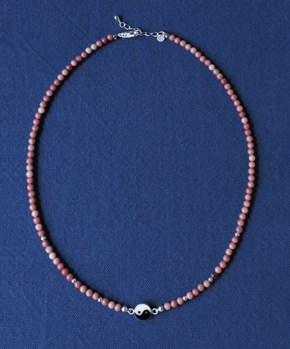 Full rhodonite yin yang necklace with lobster clasp and extender on blue cloth