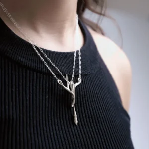 Silver bow and arrow necklace worn below the collarbone from a side angle