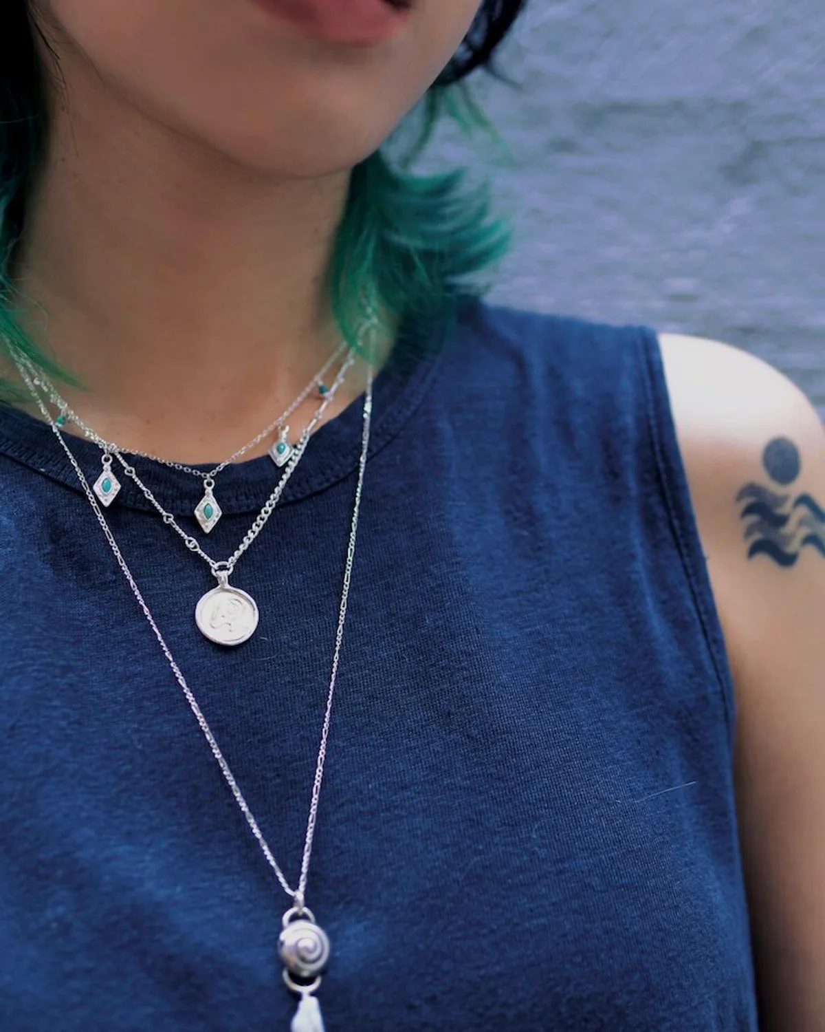 Silver Necklace Stack at Three Lengths Three silver pendant necklaces layered at graduated lengths over a navy top