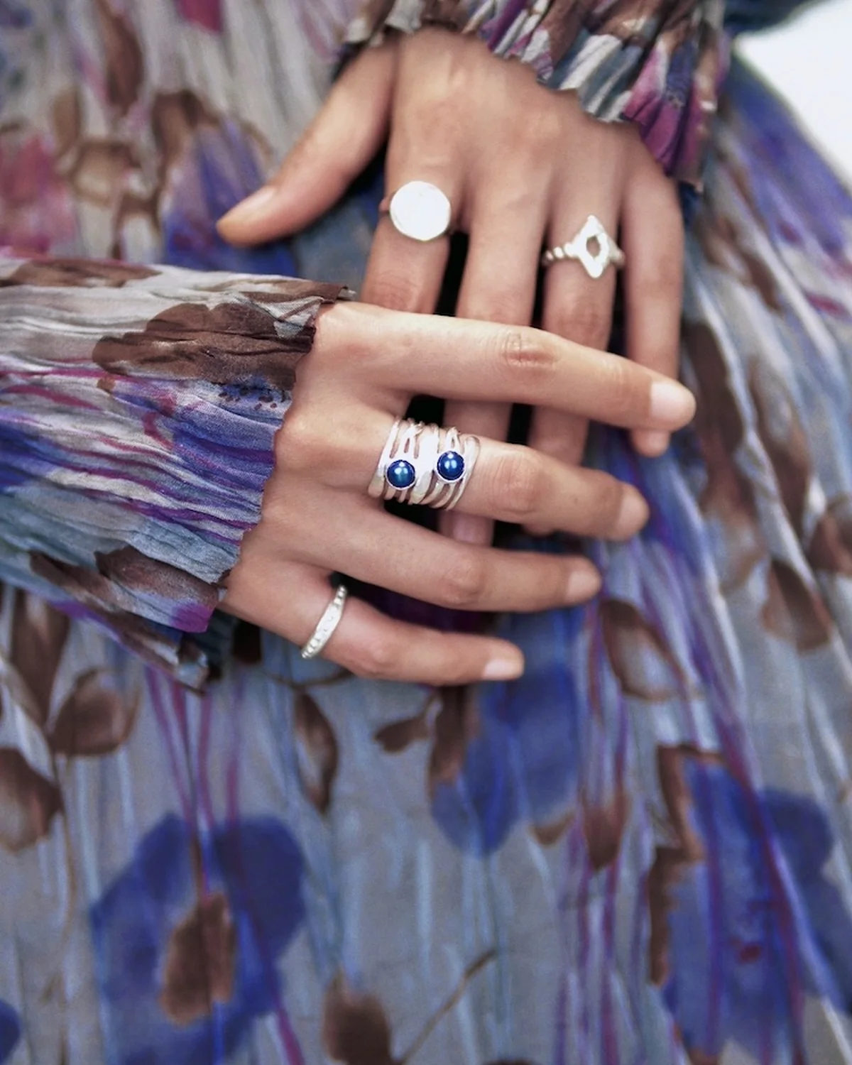 Silver rings with blue stones and geometric forms spread across both hands