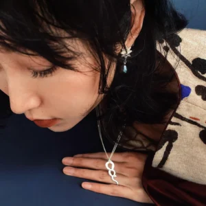 Silver snake pendant necklace worn in a dark blue editorial setting