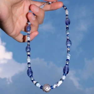 Blue lace agate necklace held against the sky with a silver spiral shell centre