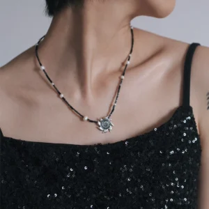 Spiral sun necklace worn at the collarbone with a black sequin dress