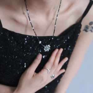 Full wearing view of a spiral sun necklace over a black sequin dress