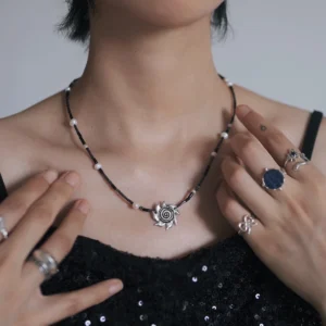 Spiral sun necklace styled with layered silver and gemstone rings