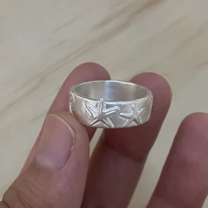 Handheld close-up of two sea stars on a wide 999 fine silver ring