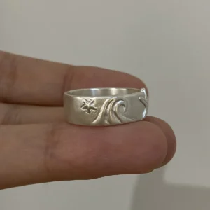 Silver starfish ring close-up with raised wave and small sea star relief