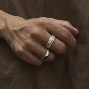 Wide silver starfish ring worn on hand beside a dark gemstone ring