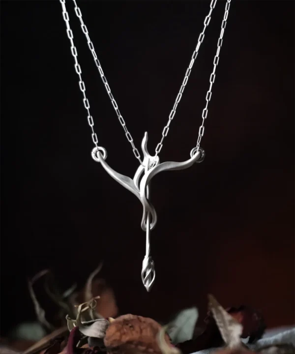 Sterling silver bow and arrow necklace suspended against a dark background