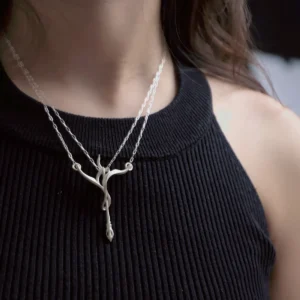 Sterling silver bow and arrow necklace worn over a black ribbed top