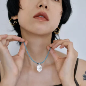 Sterling silver dragonfly necklace held at the collarbone to show its scale