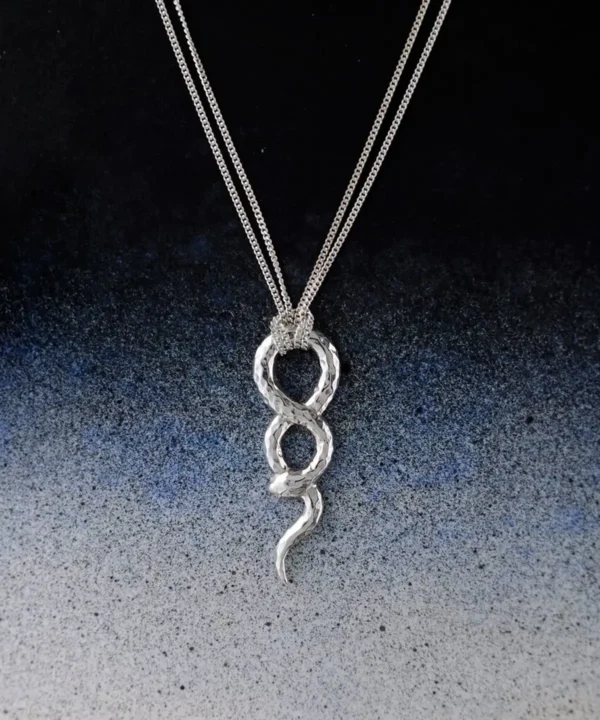 Sterling silver snake necklace with an infinity-shaped pendant and clear cubic zirconia accent on a blue-to-white background