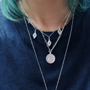 Close view of turquoise silver charms within a layered necklace arrangement
