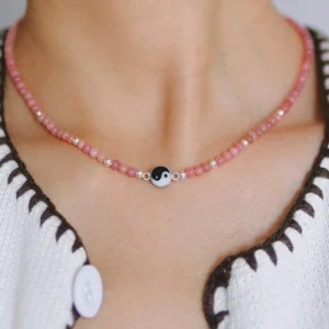 Pink rhodonite yin yang necklace worn close at the collarbone