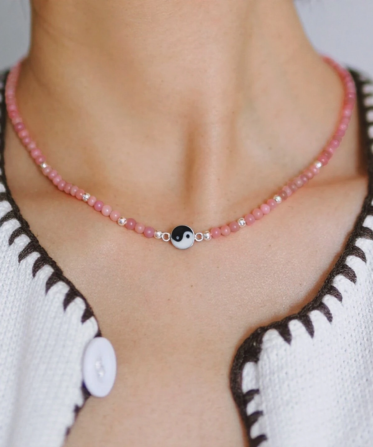 Pink rhodonite yin yang necklace worn close at the collarbone