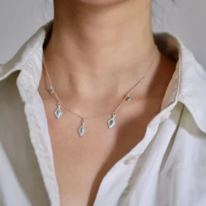 Turquoise charm necklace worn alone at the collarbone with a white shirt