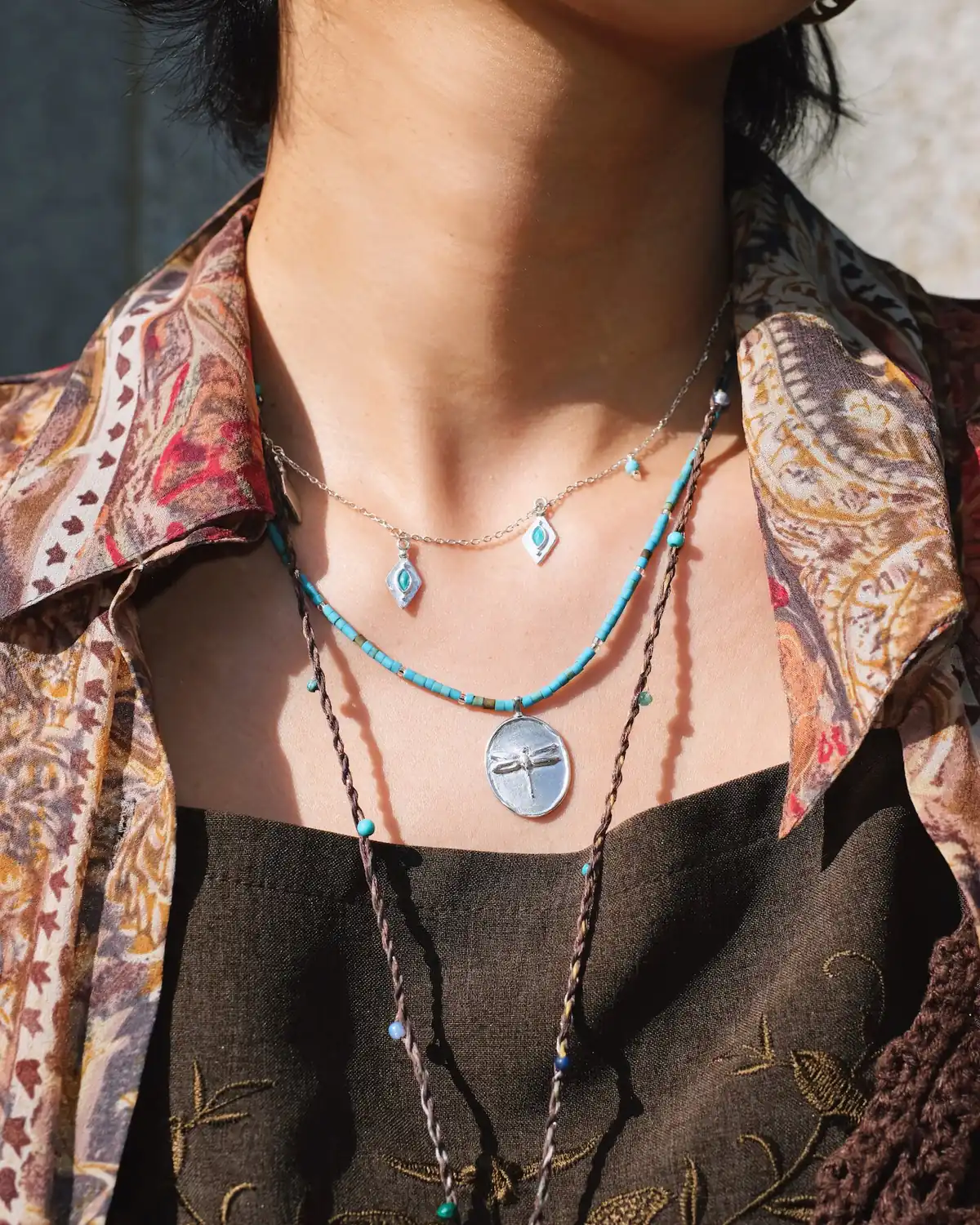 Turquoise Necklace Layers with a Patterned Shirt Turquoise charm, dragonfly pendant and long botanical necklace layered with a patterned open shirt