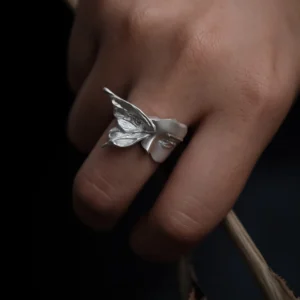 Gaze sterling silver moth ring worn on a hand, showing the raised wing and sculpted face