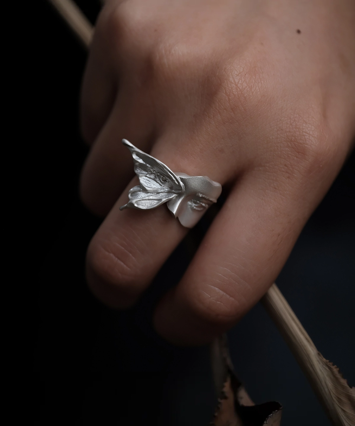 Gaze sterling silver moth ring worn on a hand, showing the raised wing and sculpted face