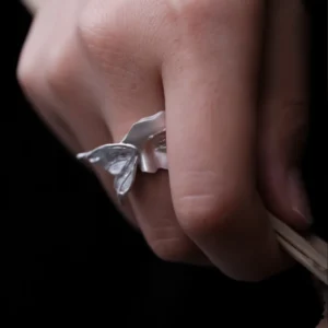 Side view of Gaze silver ring worn on a finger, showing the raised moth wing beside the sculpted face