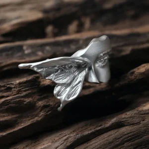 Gaze silver ring viewed from the side on dark wood, showing the textured moth wing and face profile
