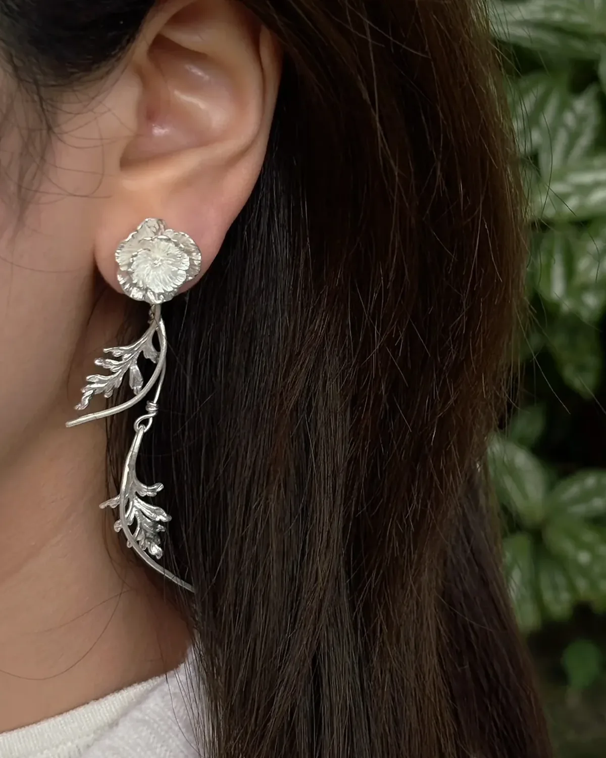 August Birth Flower Poppy Earrings Long silver poppy birth flower earring worn beside dark hair