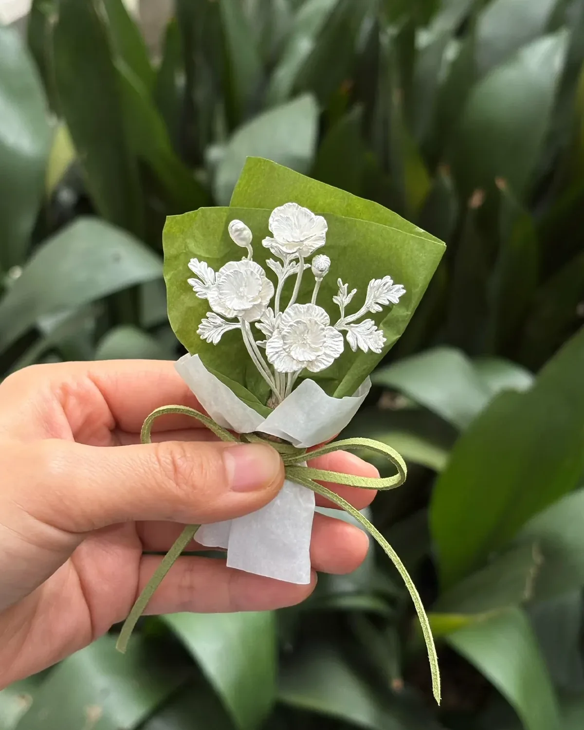 Three-Bloom Silver Poppy Bouquet Three-bloom 950 silver poppy bouquet in green wrap held in a hand