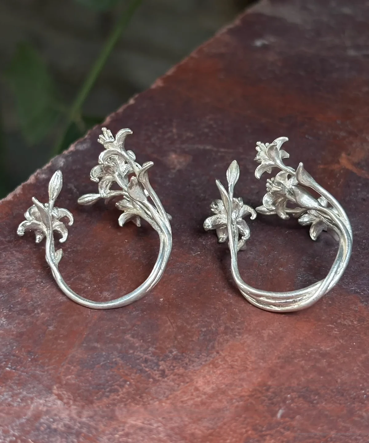 Back view of two little lily rings, with a single band on the left and an openwork band on the right